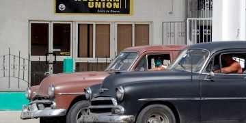 Dos autos antiguos pasan frente a una oficina de Western Unión, en La Habana, en su último día de operaciones en Cuba, el 23 de noviembre de 2020. Foto: Ernesto Mastrascusa / EFE / Archivo.