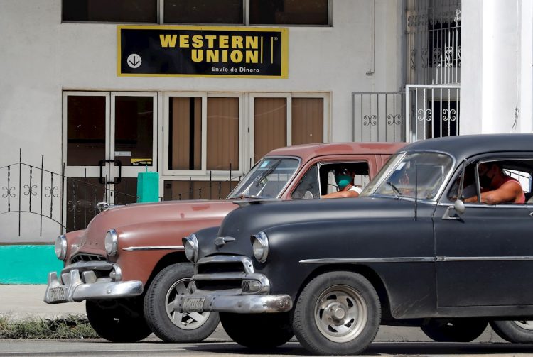 Dos autos antiguos pasan frente a una oficina de Western Unión, en La Habana, en su último día de operaciones en Cuba, el 23 de noviembre de 2020. Foto: Ernesto Mastrascusa / EFE / Archivo.