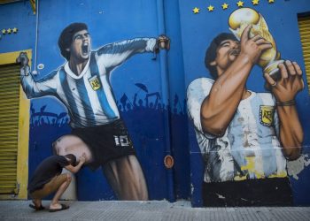 Augusto Canosa reza al tocar una pintura de Diego Maradona cerca del estadio La Bombonera de Boca Juniors en Buenos Aires, Argentina, el viernes 27 de noviembre de 2020. Foto: AP/Rodrigo Abd.