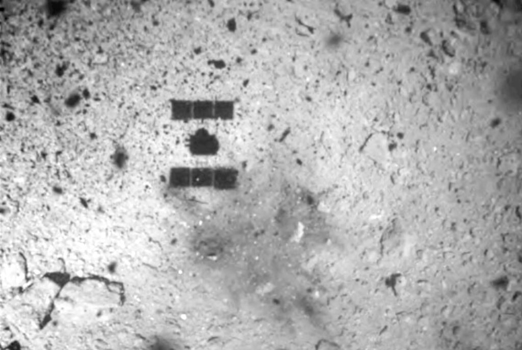 Imagen de archivo del 22 de febrero de 2019, difundida por la Agencia de Exploración Aerospacial de Japón (JAXA), y que muestra la sombra (al centro y arriba) de la nave espacial Hayabusa2 después de su descenso exitoso en el asteroide Ryugu. Foto: JAXA vía AP/ Archivo.