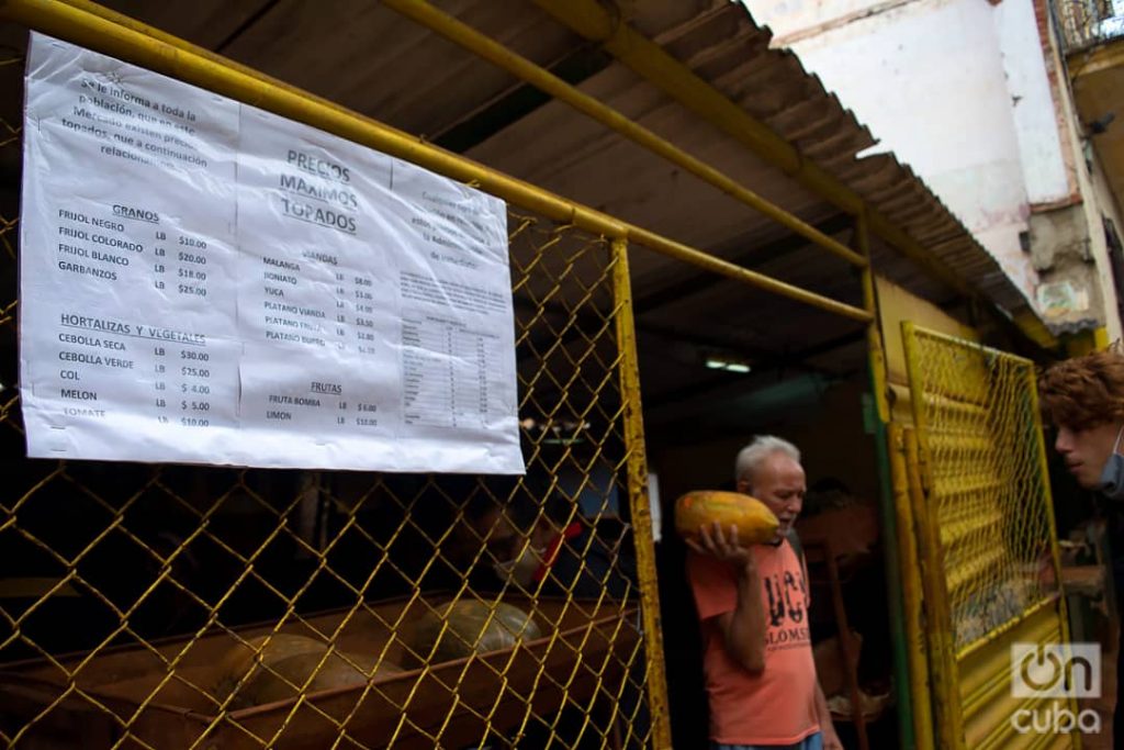 Un hombre sale con sus compras de un mercado agropecuario en La Habana. En primer plano, el listado de precios "topados" por el gobierno. Foto: Otmaro Rodríguez/Archivo OnCuba.