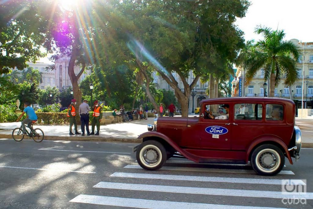 Un auto clásico pasa frente a un grupo de policías en el Parque Central de La Habana, el 1 de diciembre de 2020. Foto: Otmaro Rodríguez.
