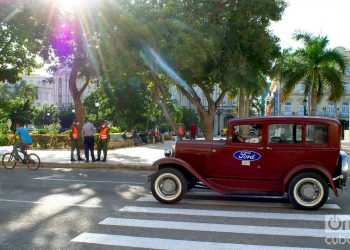 Un auto clásico pasa frente a un grupo de policías en el Parque Central de La Habana, el 1 de diciembre de 2020. Foto: Otmaro Rodríguez.