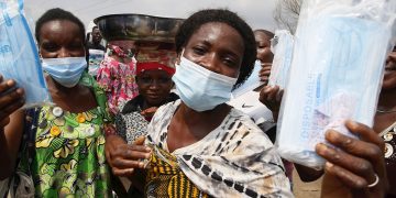 Mujeres usan y muestran mascarillas faciales donadas durante una campaña de concienciación para su empleo en Abidján, Costa de Marfil. Foto: Legnan Koula / EFE.