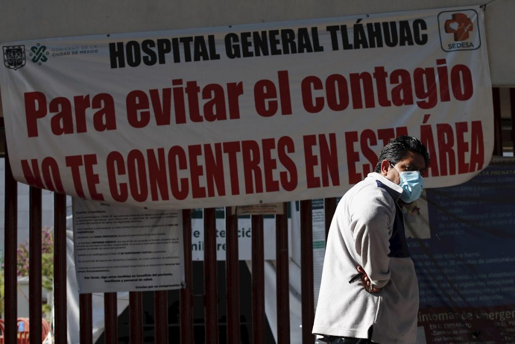 Un hombre camina frente a un letrero de advertencia de alto contagio de la COVID-19, en el Hospital General Tláhuac de Ciudad de México. Foto: José Méndez / EFE.