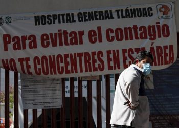 Un hombre camina frente a un letrero de advertencia de alto contagio de la COVID-19, en el Hospital General Tláhuac de Ciudad de México. Foto: José Méndez / EFE.