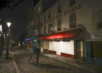 Un hombre con su bicicleta frente a varios restaurantes cerrados en Montmartre, durante el toque de queda impuesto en París por la pandemia de coronavirus. Foto: Michel Euler/AP.