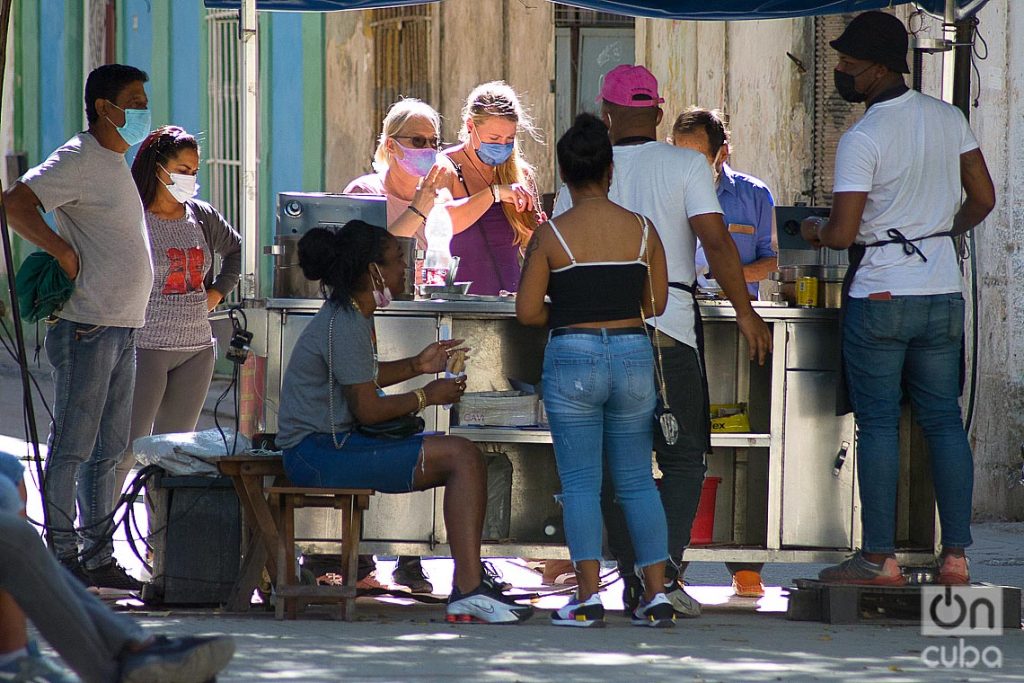 Unos turistas y otras personas en un puesto de venta de churros durante el rebrote de la COVID-19 en La Habana, en enero de 2021. Foto: Otmaro Rodríguez.