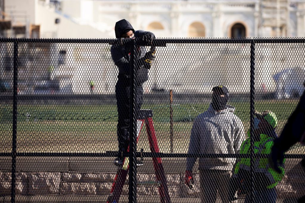 Trabajadores refuerzan la seguridad alrededor del Capitolio, al día siguiente del asalto por parte de seguidores de Donald Trump. Foto: Michael Reynolds / EFE.
