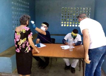 Un trabajador de la salud tomando la temperatura a una mujer en un punto de control holguinero. Foto: Trabajadores.