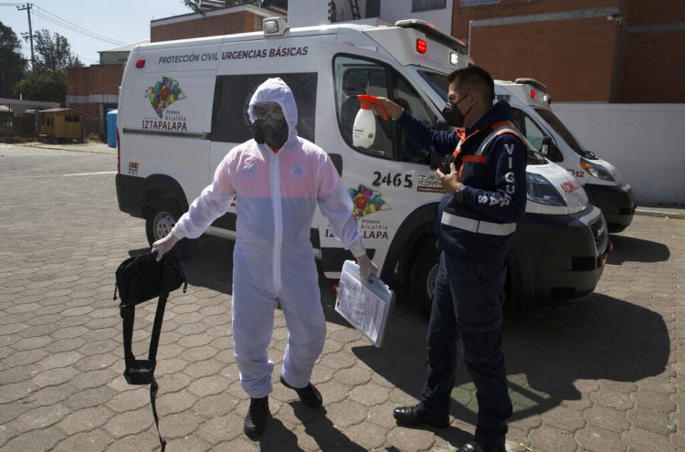 Un paramédico desinfecta a una persona después del traslado de un enfermo de COVID-19 a un hospital en la alcaldía de Iztapalapa, en la Ciudad de México. Foto: Marco Ugarte/AP.