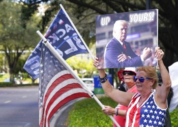 Seguidores de Donald Trump ondean banderas y letreros a los conductores que pasan frente al centro de convenciones en la Conferencia de Acción Política Conservadora el sábado 27 de febrero de 2021 en Orlando, Florida. Foto: AP/John Raoux.