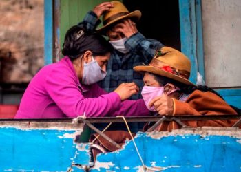 Una mujer le arregla el nasobuco a su madre en una casa en Pamplona Alta, periferia sur de Lima. Foto: Ernesto Benavides/ AFP.