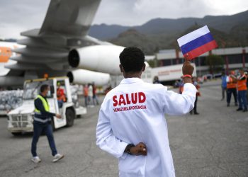 Un trabajador de la salud sostiene una bandera nacional rusa mientras es descargado un cargamento de la vacuna rusa Sputnik V contra el COVID-19, en el Aeropuerto Internacional Simón Bolívar en Maiquetía, Venezuela, el sábado 13 de febrero de 2021  Foto: Matías Delacroix/Ap.