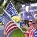 Seguidores de Donald Trump ondean banderas y letreros a los conductores que pasan frente al centro de convenciones en la Conferencia de Acción Política Conservadora el sábado 27 de febrero de 2021 en Orlando, Florida. (AP Foto/John Raoux)