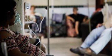 Una paciente con COVID-19 permanece sentada con una máscara de oxígeno en el Hospital de Clínicas, en San Lorenzo, Paraguay. Foto: Nathalia Aguilar / EFE.
