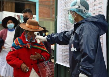 Un funcionario electoral mide la temperatura a una mujer antes de ingresar a su local de votación, en el Cusco, Perú, el domingo 11 de abril de 2021. Foto: Stringer / EFE.