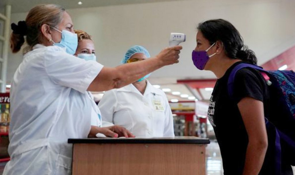 Personal sanitario cubano toma la temperatura a una viajera a su arribo a un aeropuerto de la Isla. Foto: minsap.cu / Archivo.