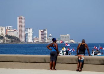 Personas observan las embarcaciones que participa en la regata contra el bloqueo, en el malecón de La Habana. Foto: Yander Zamora/Efe.