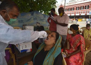 Un trabajador sanitario toma a una mujer una muestra para una prueba diagnóstica del coronavirus SARS-CoV-2, en Chennai, la India. Foto: Idrees Mohammed / EFE.