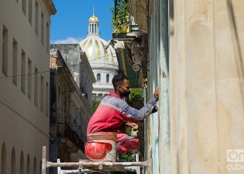 Constructor repara la fachada de un edificio en la calle Obrapía, La Habana. Foto: Otmaro Rodríguez