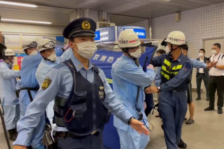La policía escolta a rescatistas que llevan a una persona herida después de un ataque con cuchillo en un tren en Tokio. Foto: Al Jazeera.