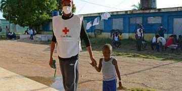 Un voluntario cubano de la Cruz Roja junto a un niño haitiano en un campamento de migrantes en el norte de Cuba. Foto: Rodolfo Blanco / ACN / Archivo.