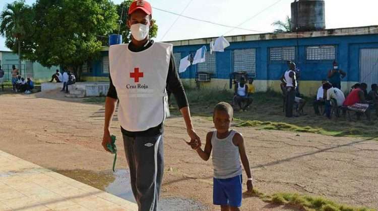 Un voluntario cubano de la Cruz Roja junto a un niño haitiano en un campamento de migrantes en el norte de Camagüey, Cuba. Foto: Rodolfo Blanco / ACN.
