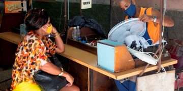 Una mujer espera que un mecánico le repare un ventilador, en un taller de equipos electrodomésticos en La Habana. Foto: Yander Zamora / EFE.