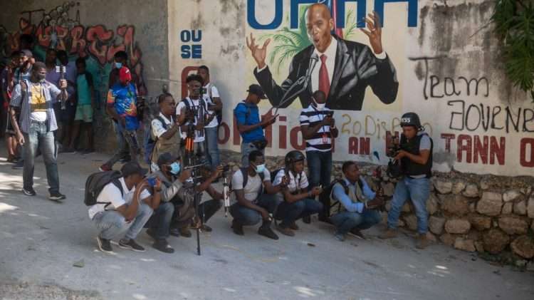 Varios haitianos, junto a un mural del presidente asesinado, Juvenal Moïse, en Puerto Príncipe. | Foto: EFE