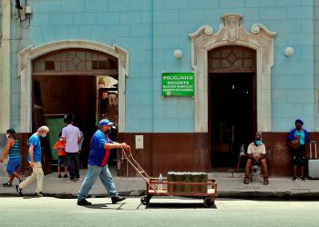 Un hombre mientras camina con una carretilla frente a un policlínico en La Habana, provincia con una de las tasas de incidencias más bajas al cierre de mes. Foto: Ernesto Mastrascusa/Efe.