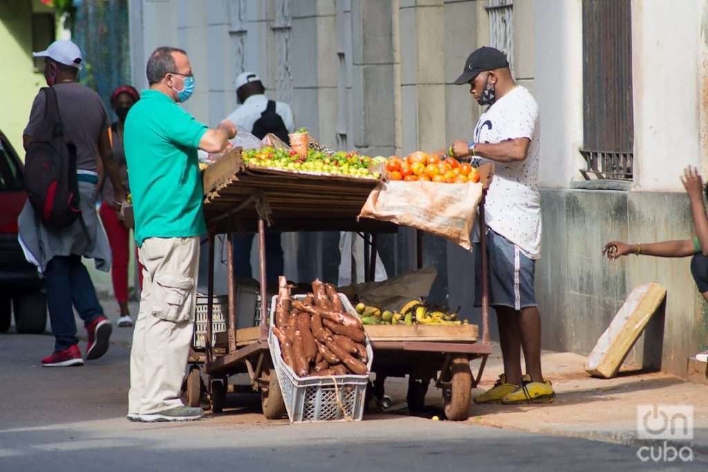 Un hombre compra a un vendedor ambulante de productos agrícolas en La Habana. Foto: Otmaro Rodríguez.