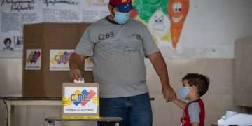 Un hombre junto a su hijo vota en un colegio electoral de Caracas, durante las elecciones regionales de Venezuela, el domingo 21 de noviembre de 2021. Foto: Rayner Peña / EFE.