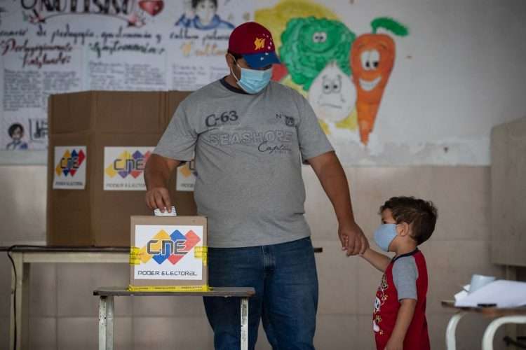 Un hombre junto a su hijo vota en un colegio electoral de Caracas, durante las elecciones regionales de Venezuela, el domingo 21 de noviembre de 2021. Foto: Rayner Peña / EFE.