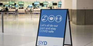 Cartel sobre medidas de protección frente a la COVID-19 en el aeropuerto de Sidney, Australia. Foto: James Gourley / EFE.