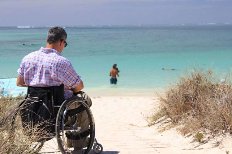 Persona con discapacidad disfruta de una playa como turista. Foto: Organización Mundial de Turismo.