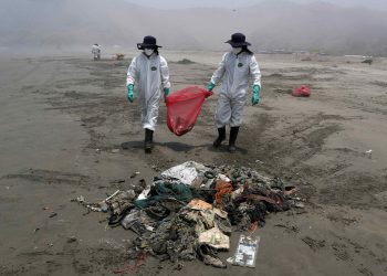Personal de limpieza limpia y recoge basura en la playa Cavero en el distrito de Ventanilla en Lima (Perú). Foto: Paolo Aguilar/Efe/Archivo.