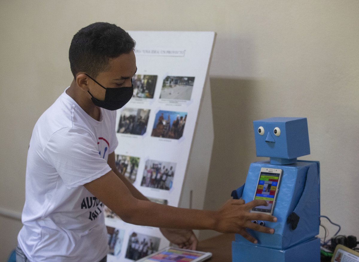 El niño Abel Robago posa junto al robot con el que ganó un concurso nacional de robótica, en el Club de Computación Arrollo I, en La Habana. Foto: Yander Zamora / EFE.