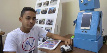 El niño cubano Abel Robago posa junto al robot con el que ganó un concurso nacional de robótica, en el Club de Computación Arrollo I, en La Habana. Foto: Yander Zamora / EFE.