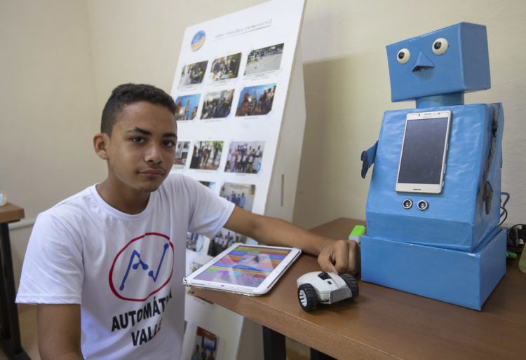 El niño cubano Abel Robago posa junto al robot con el que ganó un concurso nacional de robótica, en el Club de Computación Arrollo I, en La Habana. Foto: Yander Zamora / EFE.