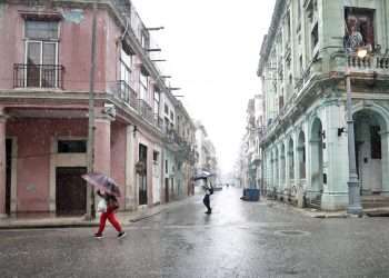 Varias personas caminan por una calle bajo un fuerte aguacero en La Habana (Cuba).  Foto: Ernesto Mastrascusa/Efe.