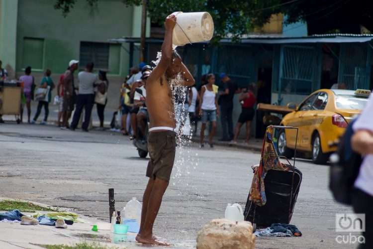 Un hombre se baña en plena calle para refrescarse del calor, en La Habana. Foto: Otmaro Rodríguez.