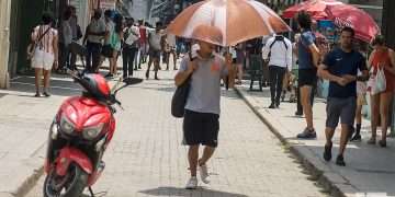 Un hombre se protege del sol con una sombrilla, en la calle Obispo de La Habana. Foto: Otmaro Rodríguez.