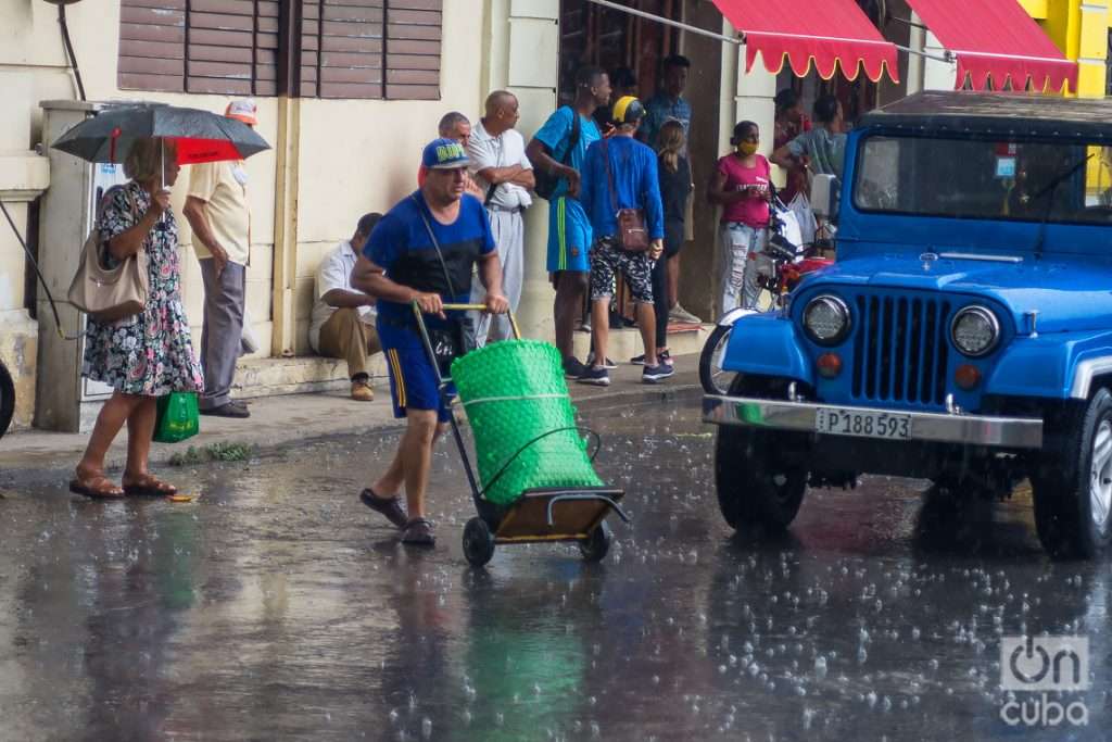 Personas en una calle de La Habana durante una lluvia de verano. Foto: Otmaro Rodríguez.