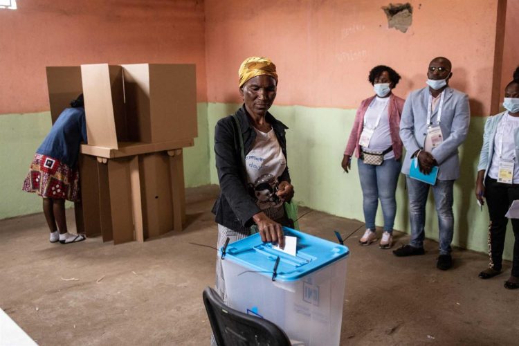 Delegados de los partidos político supervisa el voto de una angolana. | Foto: Lusa