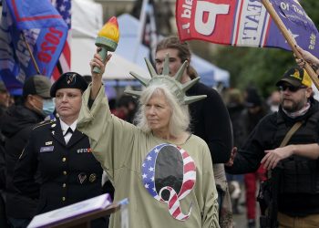Una mujer vestida como la Estatua de la Libertad con la letra Q en su vestimenta en referencia a QAnon en un acto en apoyo a Trump. Foto: Ted S. Warren/AP.