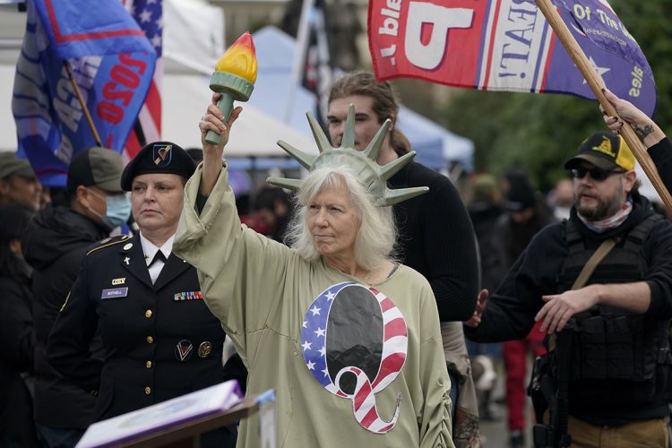 Una mujer vestida como la Estatua de la Libertad con la letra Q en su vestimenta en referencia a QAnon en un acto en apoyo a Trump. Foto: Ted S. Warren/AP.