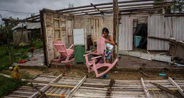 Una mujer intenta recuperar sus pertenencias de lo que queda de su casa tras el paso del huracán Ian. Foto: AP.