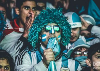 Hincha de Argentina en la grada con gafas y peluca azules muerde la camiseta de la selección mientras mira un partido de Mundial Foto: Kaloian
