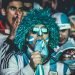 Hincha de Argentina en la grada con gafas y peluca azules muerde la camiseta de la selección mientras mira un partido de Mundial Foto: Kaloian